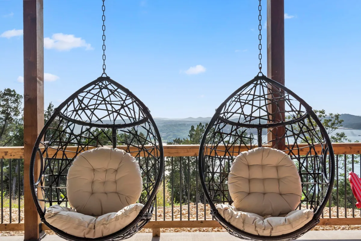 This exterior scene showcases hanging chairs along a wooden railing, overlooking a picturesque landscape. The scene evokes a sense of calm, with guests relaxing, reading, or socializing while enjoying the tranquil surroundings. The image highlights the property's potential for both peaceful downtime and social connection with nature as a backdrop.
