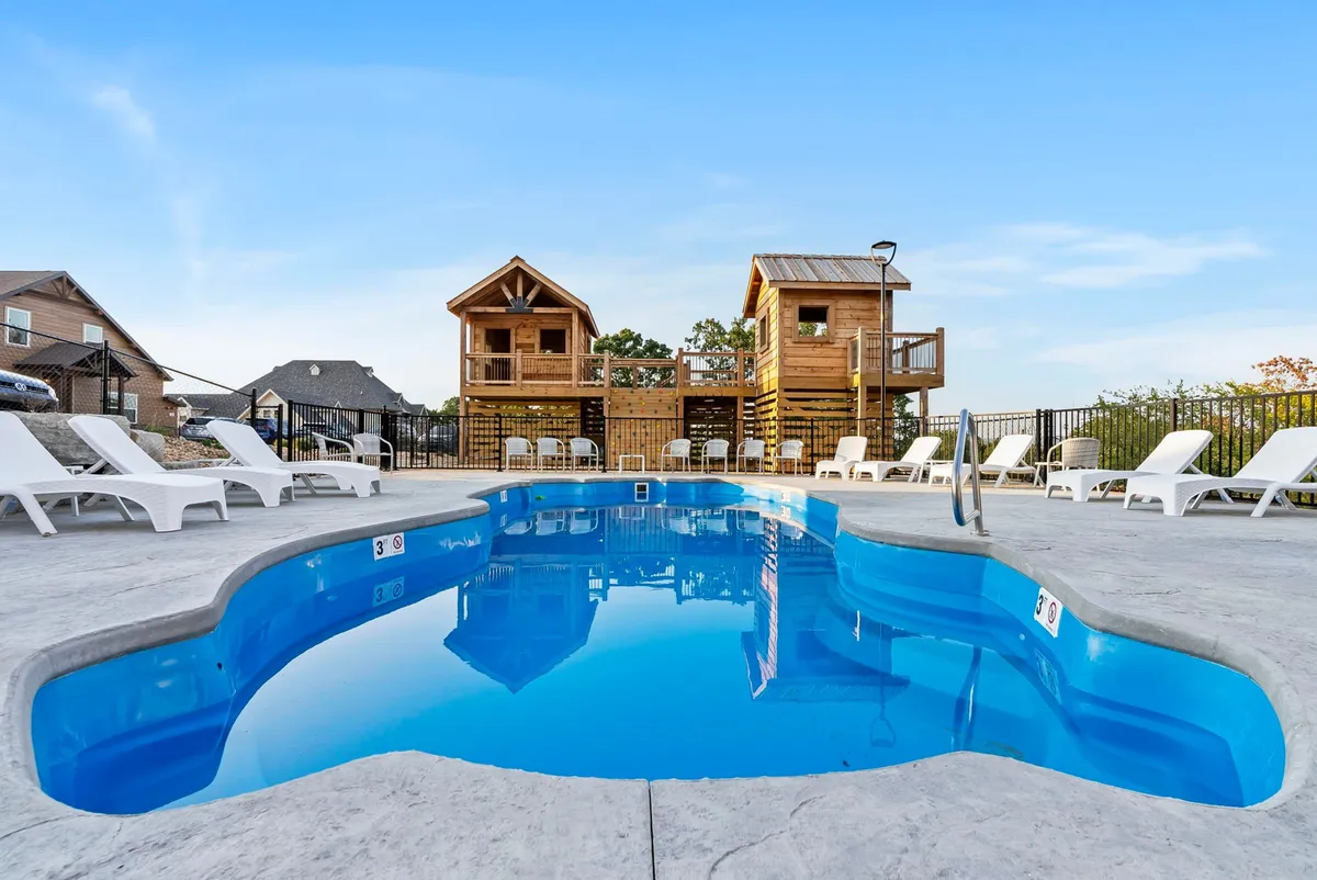 This exterior shot displays a swimming pool surrounded by wooden cabins and lounge chairs, evoking a sense of leisure and group fun. The outdoor space is ideal for gatherings and casual competition, hinting at the availability of lawn games and social activities outside.