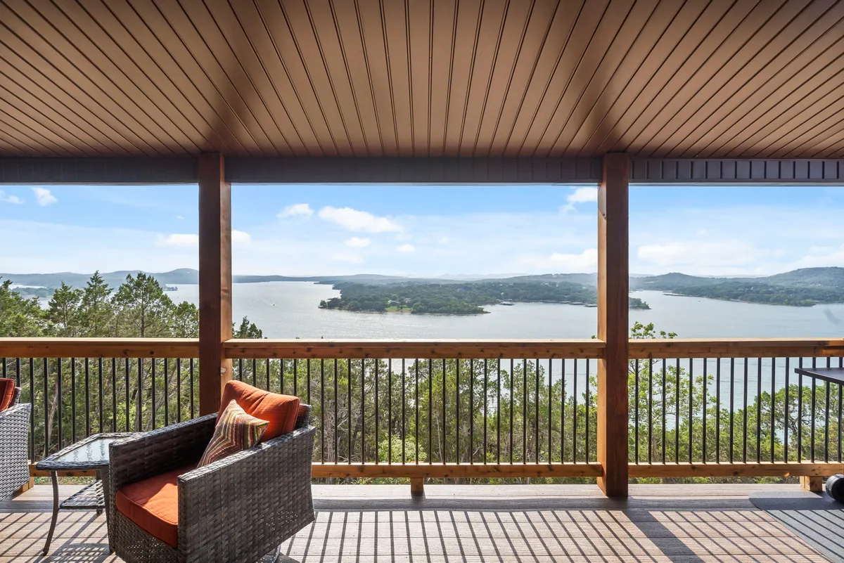 The hero image showcases an expansive, tranquil lake view from an elevated wooden deck, complete with comfortable outdoor seating and a sturdy railing. The scene suggests a perfect spot for guests to relax, gather with friends or family, and enjoy the beauty of nature, with the sun shimmering over Table Rock Lake and the surrounding hills.