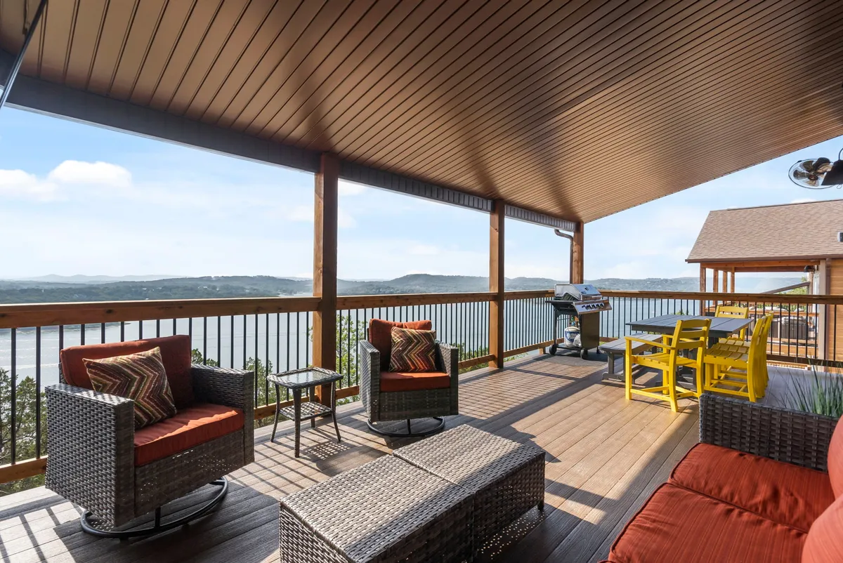 This exterior shot captures a comfortable seating area on a deck with a grill and a scenic view of the lake. The deck is well-appointed for both relaxing and dining, with the grill suggesting outdoor meals and the expansive vista reinforcing the property's strong indoor-outdoor living connection.